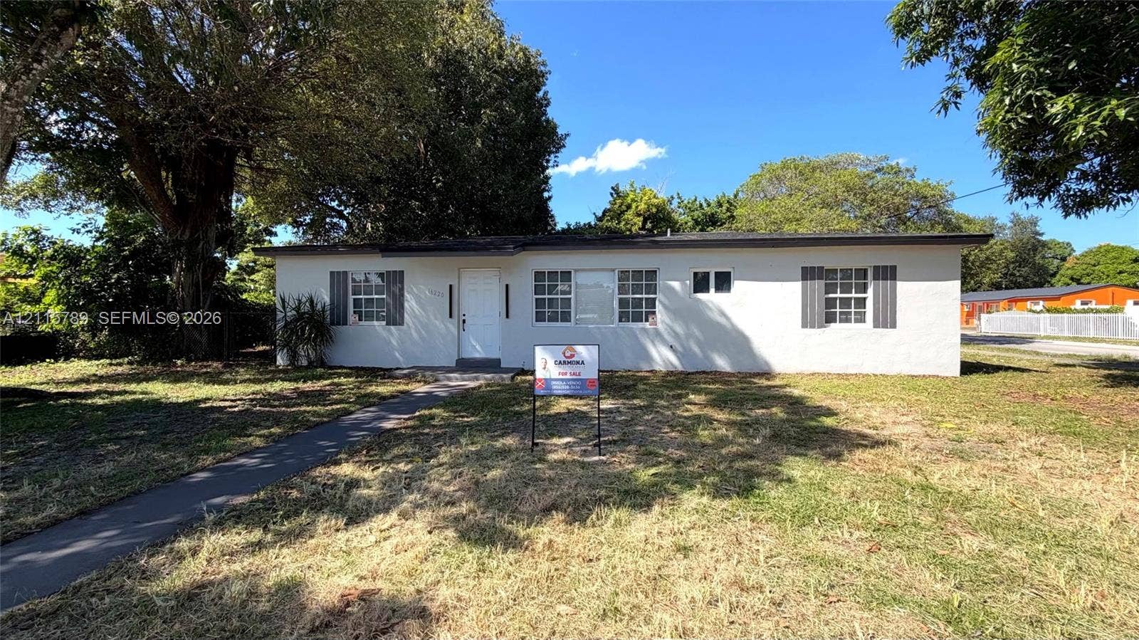 16220 NW 28th Place, Miami Gardens, FL 33054 Single-story residence featuring a painted masonry exterior, shuttered windows, and a paved walkway