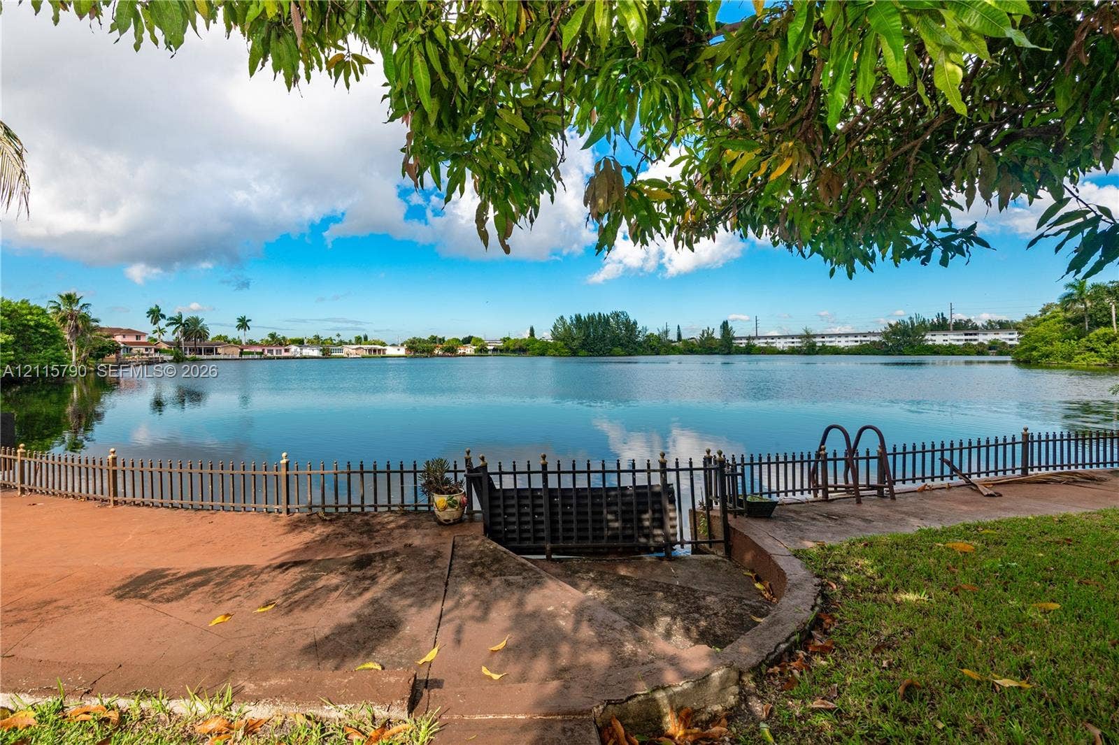 9120 NW 12th Avenue, Miami, FL 33150 Waterfront grounds featuring a concrete terrace, perimeter metal fencing, and built-in metal stairs
