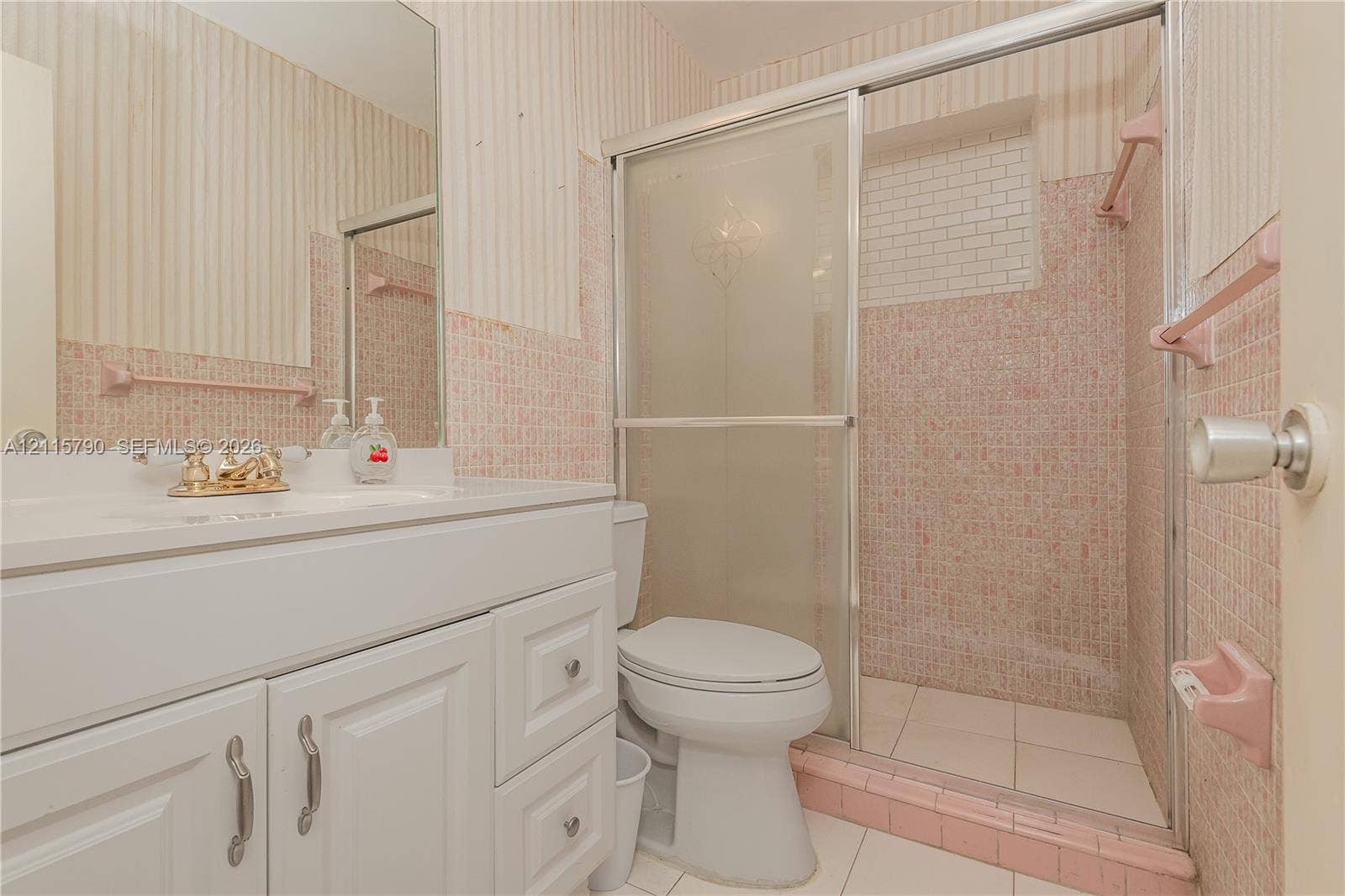 9120 NW 12th Avenue, Miami, FL 33150 Bathroom featuring a white vanity with integrated basin, polished metal hardware, a glass-enclosed shower, tiled wall finishes, and a wall-mounted mirror