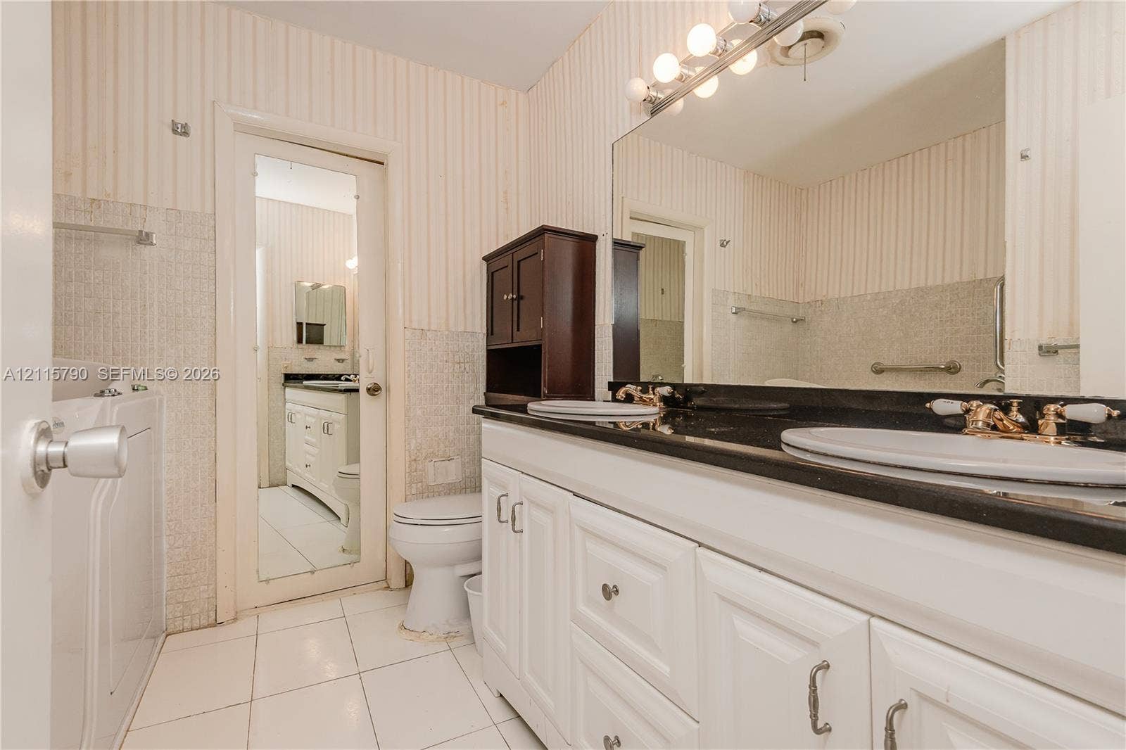 9120 NW 12th Avenue, Miami, FL 33150 Double vanity featuring white cabinetry, a dark countertop, integrated dual sinks, and an expansive wall-mounted mirror
