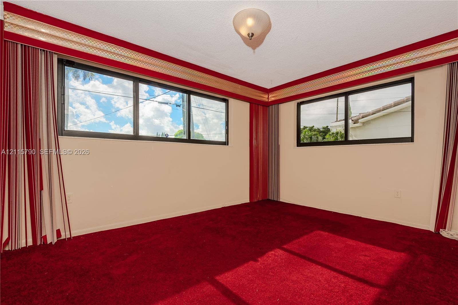 9120 NW 12th Avenue, Miami, FL 33150 Corner room featuring dual-aspect horizontal windows, ceiling-mounted flush light fixture, and wall-to-wall carpeting