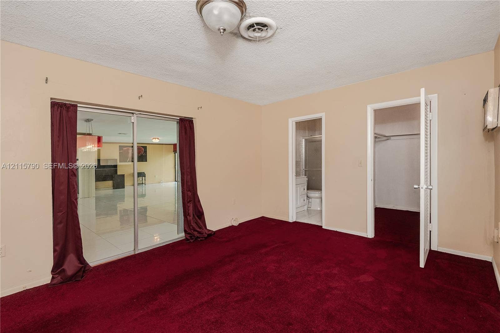 9120 NW 12th Avenue, Miami, FL 33150 Room interior featuring carpeting, sliding glass doors, and dual access points to a bathroom and closet