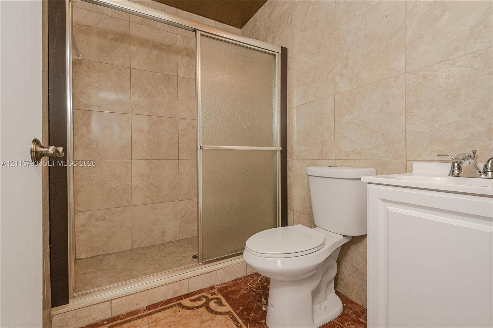 9120 NW 12th Avenue, Miami, FL 33150 Walk-in shower with sliding glass enclosure and tiled surround, white vanity, and toilet
