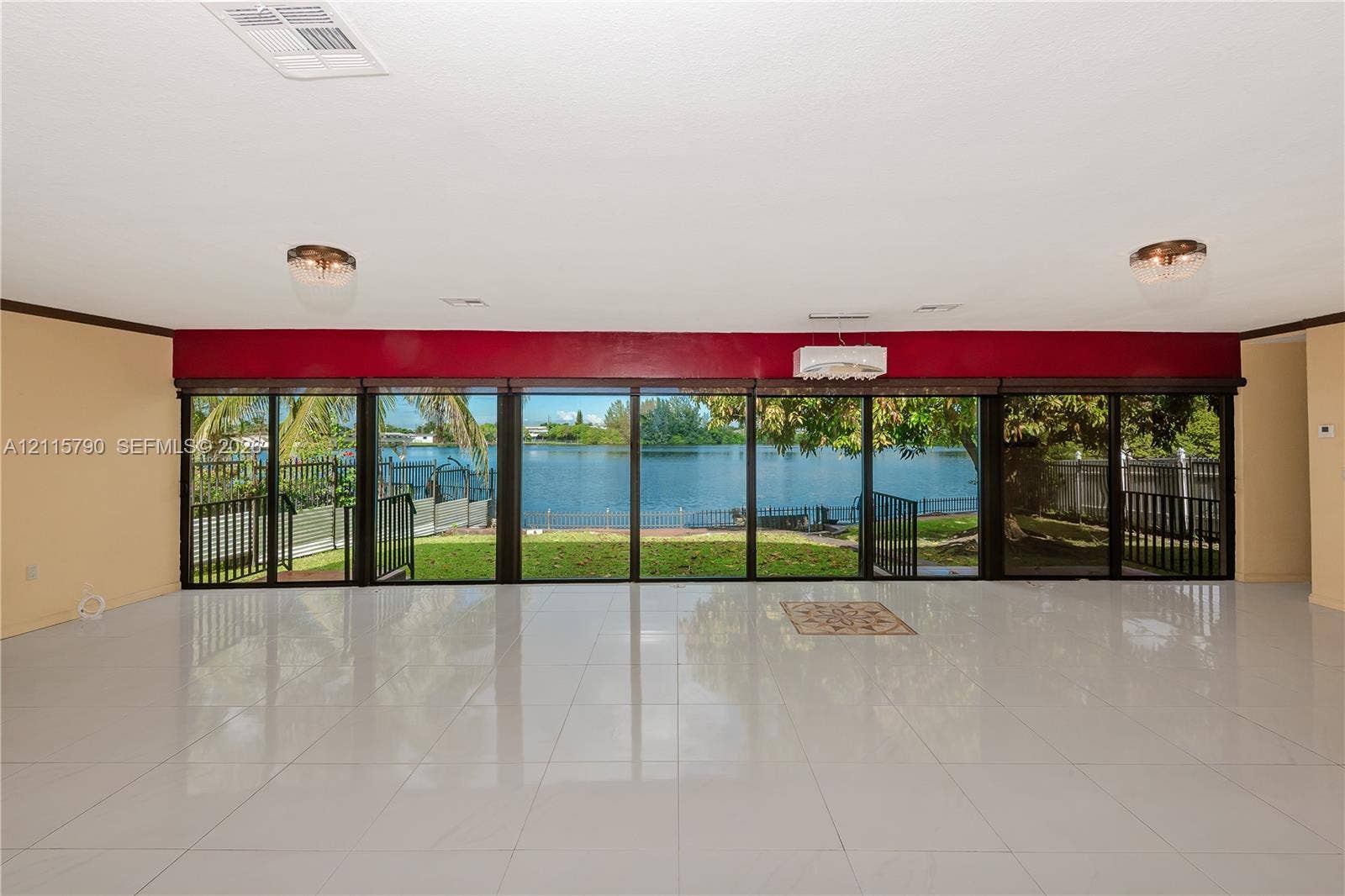 9120 NW 12th Avenue, Miami, FL 33150 Expansive living area featuring large-format tile flooring, recessed lighting, and an expansive wall of floor-to-ceiling glass sliding doors with water frontage