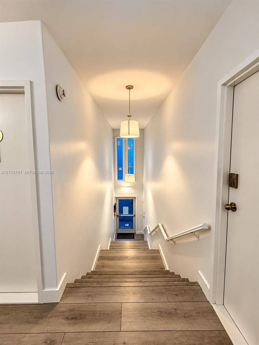 1455 Michigan Avenue, #19B, Miami Beach, Miami Beach, FL 33139 Staircase featuring wood-finish flooring, white walls, dual hanging pendant lights, and a white handrail