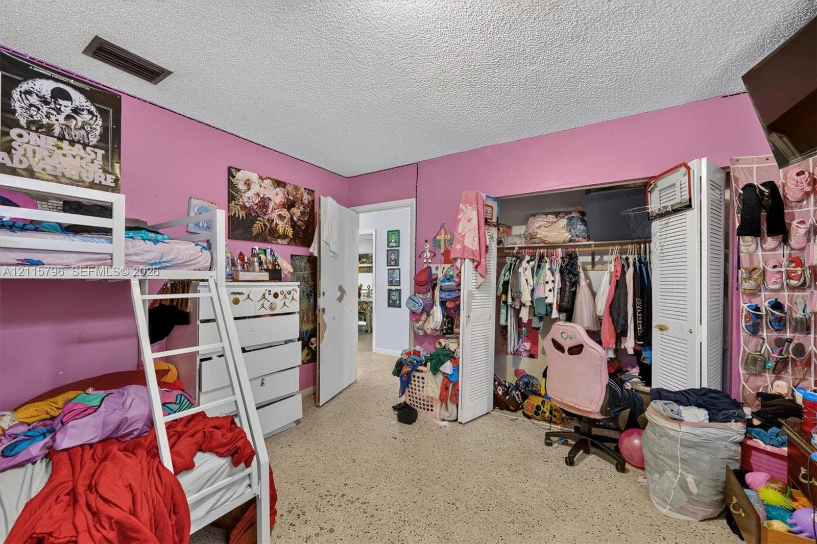 Bedroom interior featuring textured ceiling, louvered closet doors, and hard-surface flooring