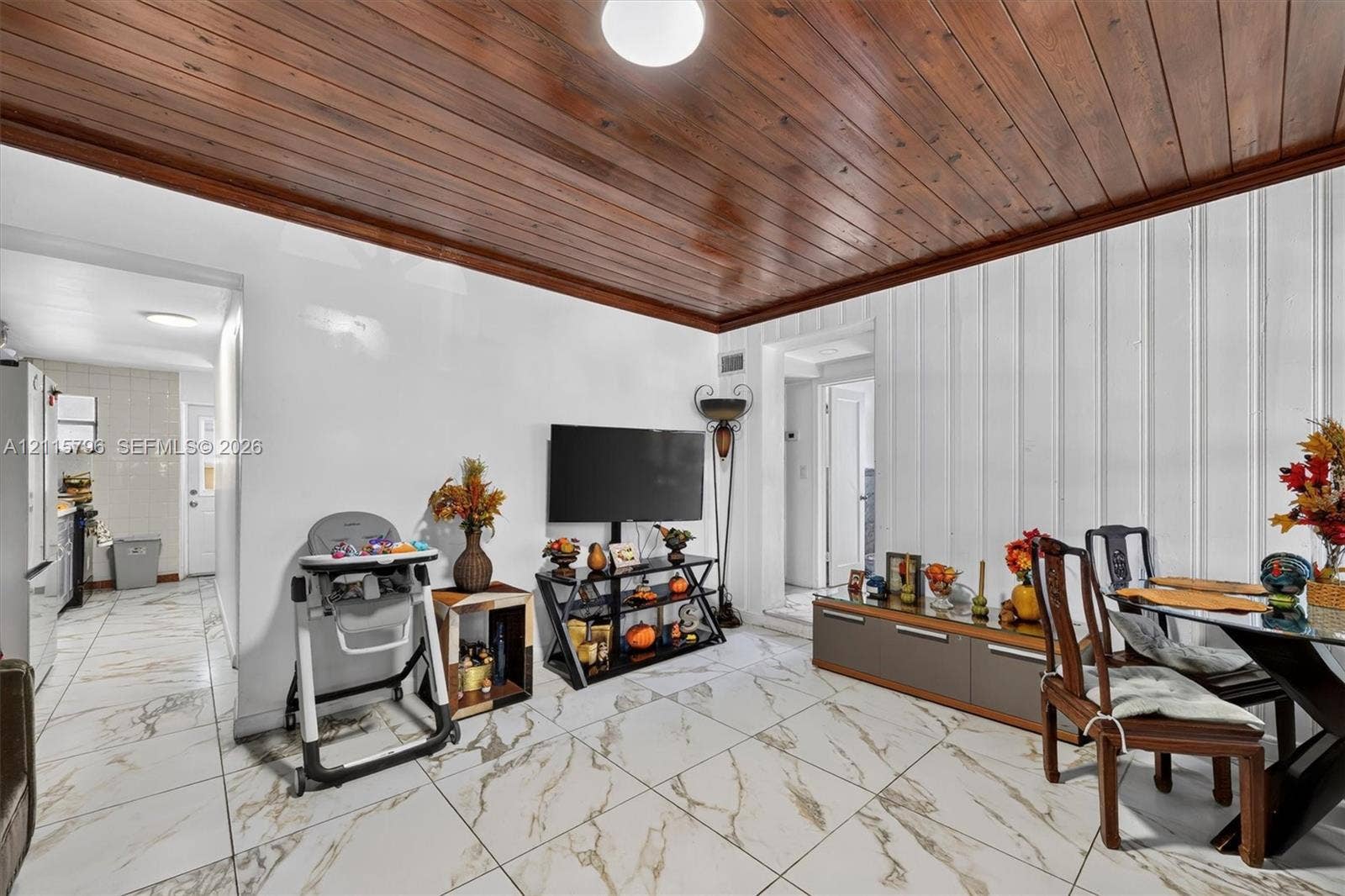Vaulted wood-plank ceiling featuring natural finish, floor-to-ceiling vertical paneled walls, and large-format porcelain tile flooring with gold-toned veining