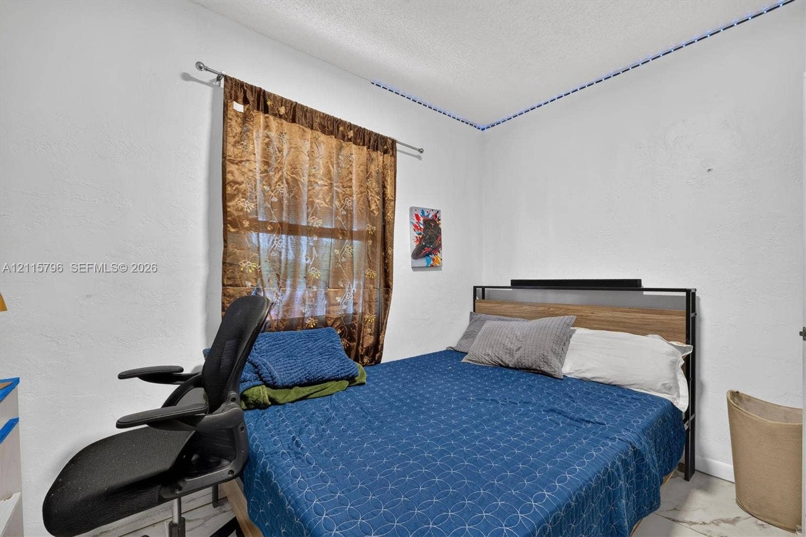 Room featuring white walls, a single-pane window with a metal curtain rod, and stone-finish flooring