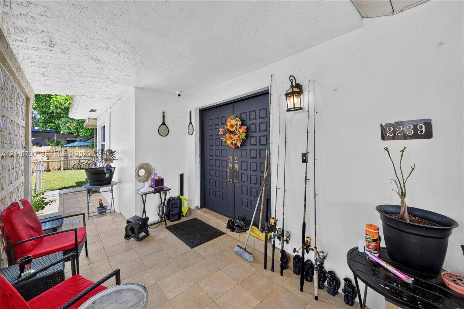 Covered entryway featuring tiled flooring, double entry doors with a grid-panel design, and an attached wall-mounted lantern light fixture
