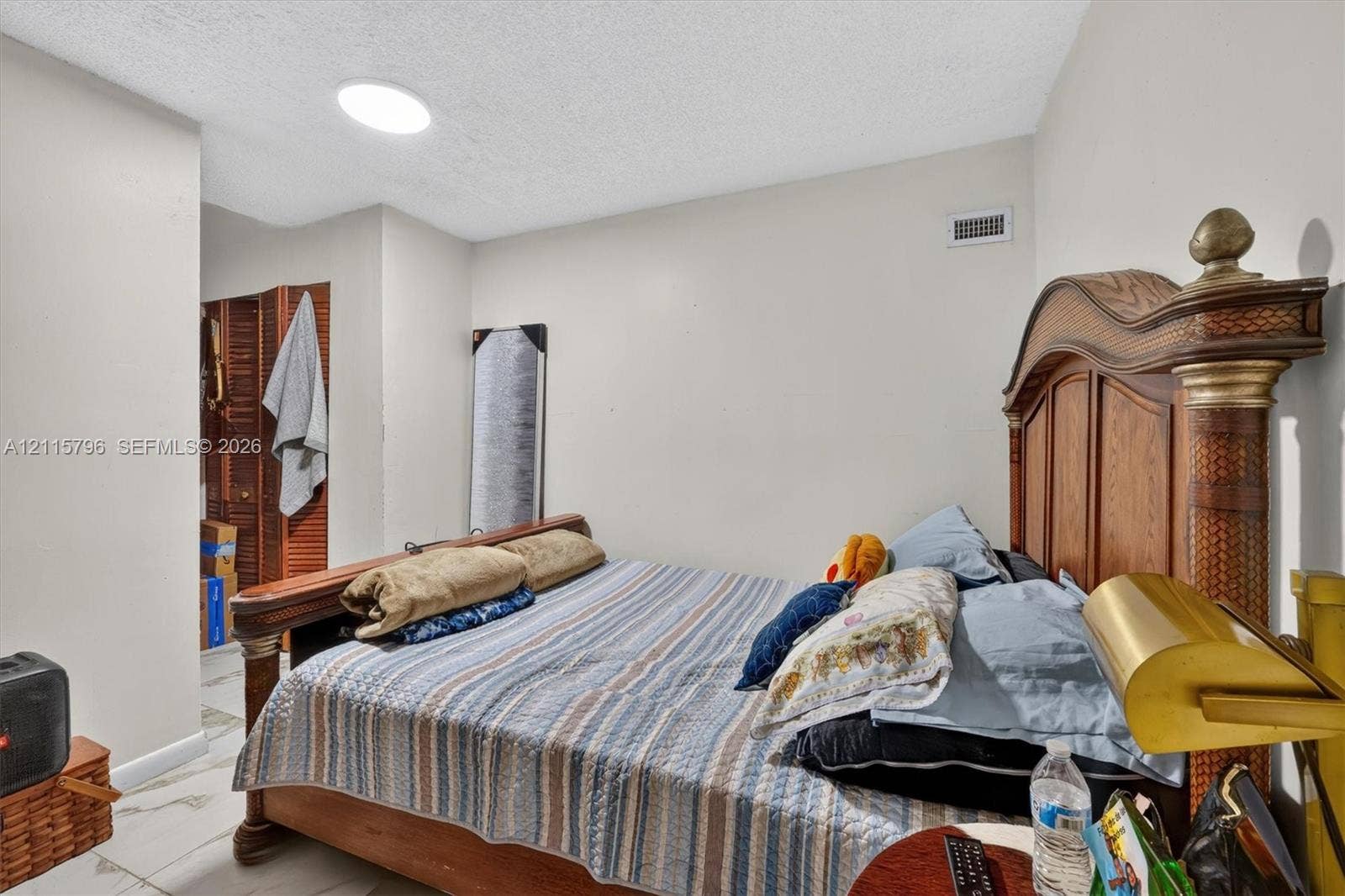 Neutral wall paint, light-toned flooring with stone-finish tile, and a built-in closet featuring bi-fold louvered doors