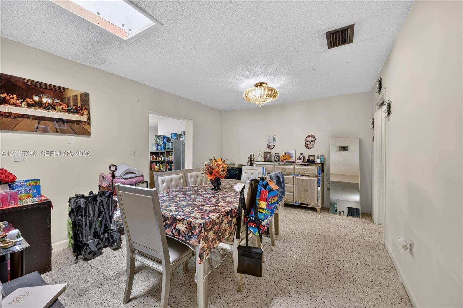 Room featuring a skylight, flush-mount crystal chandelier, and terrazzo flooring