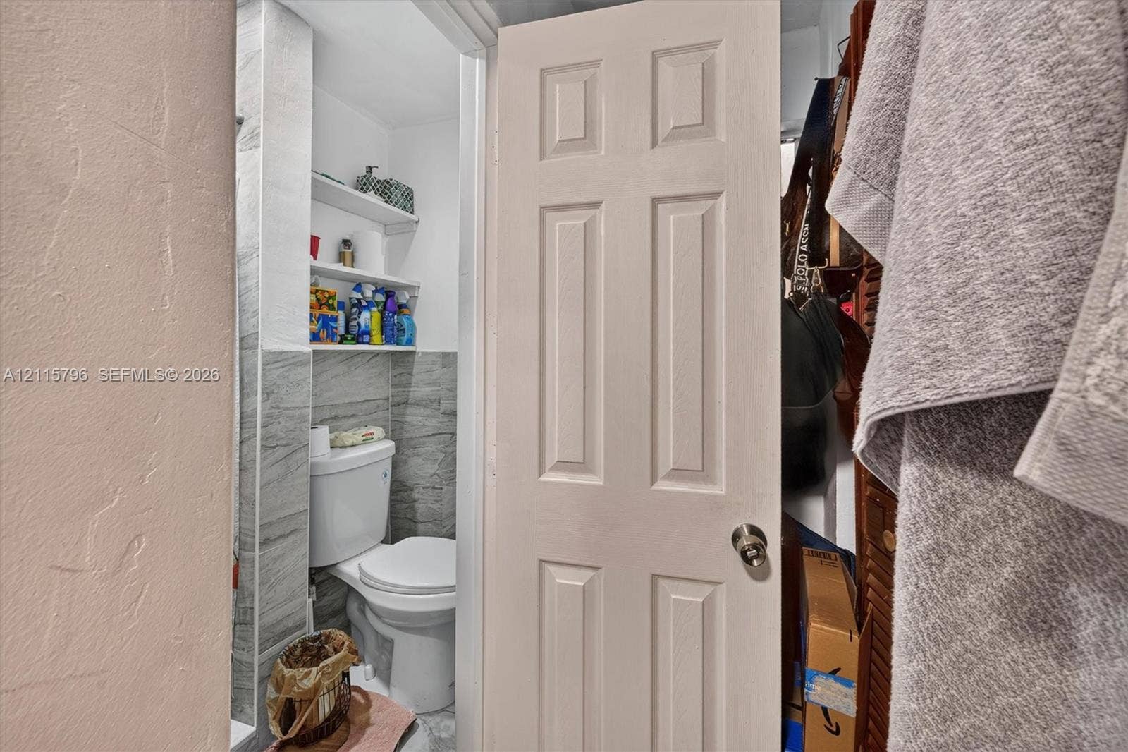 Bathroom featuring gray stone-patterned wall tile, two built-in storage shelves, and a standard-height toilet