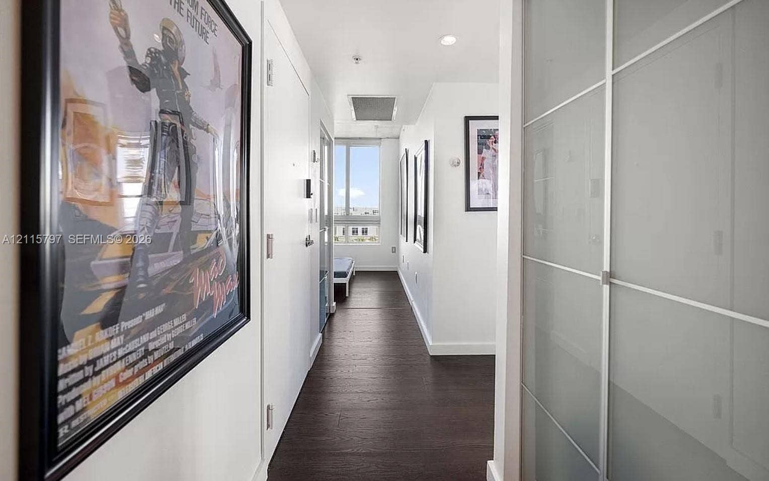Hallway featuring dark wood-finish flooring, recessed lighting, and a closet with sliding frosted glass panels