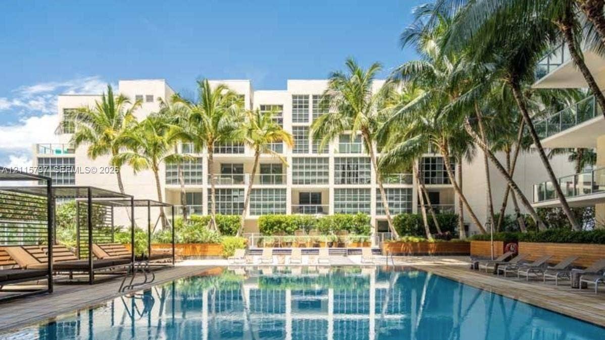 Swimming pool featuring a wood-plank deck, built-in poolside cabana structures, and perimeter landscaping