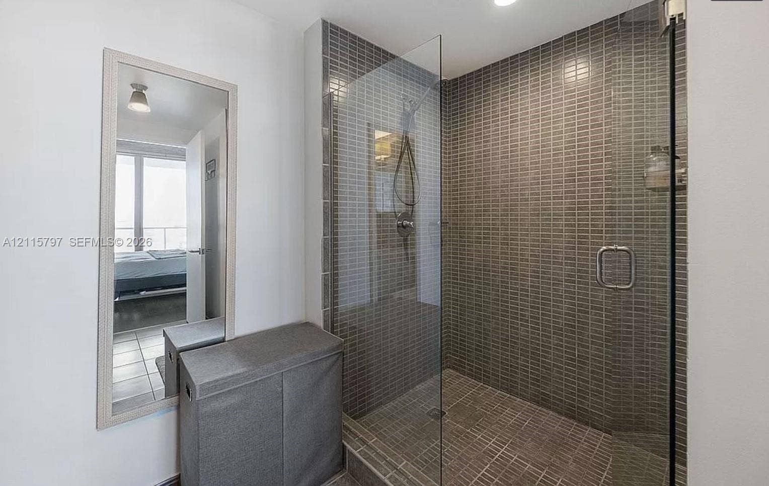 Walk-in shower featuring floor-to-ceiling mosaic tile, glass enclosure, and wall-mounted shower head