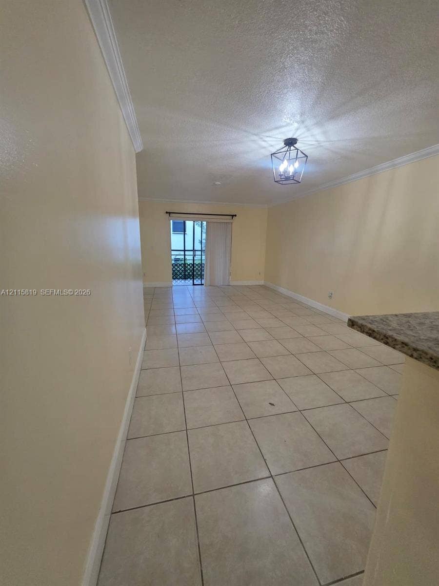 831 NE 207th Lane, #2-203, Miami, Miami, FL 33179 Neutral tile flooring, crown molding, modern geometric cage-style chandelier, and sliding glass door with exterior access