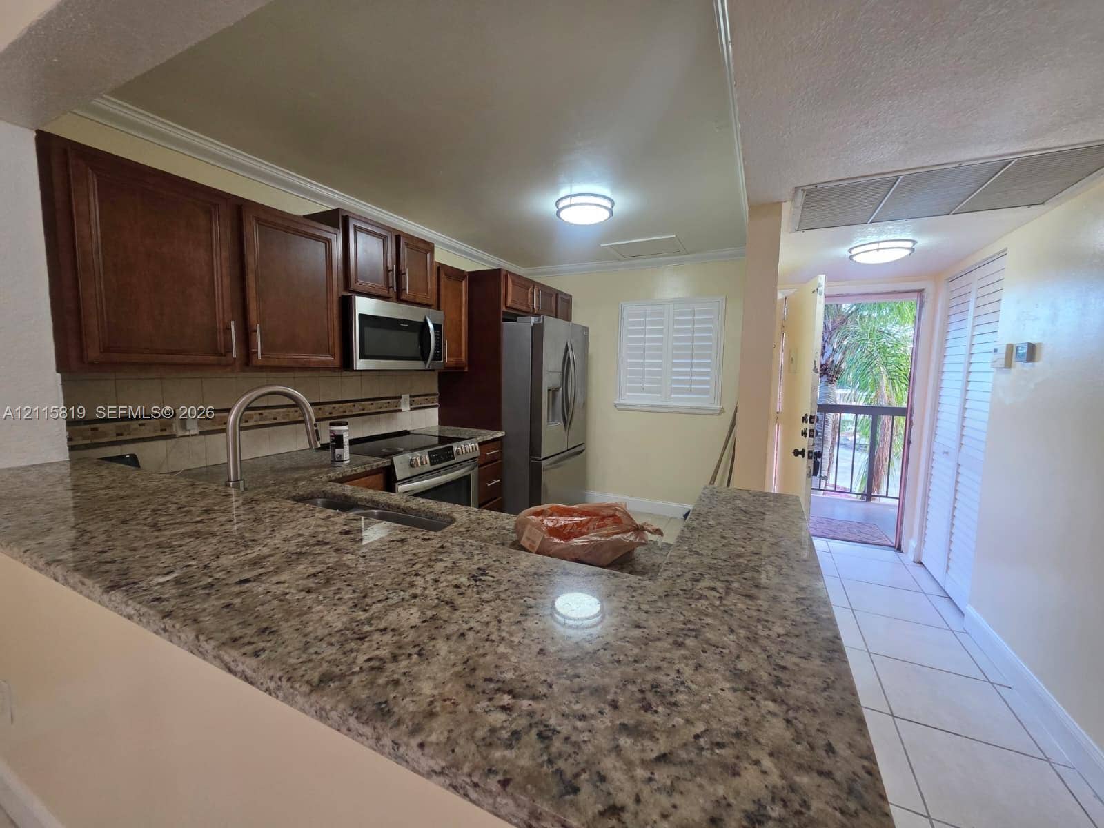 831 NE 207th Lane, #2-203, Miami, Miami, FL 33179 Kitchen featuring stone countertops, dark wood-finish cabinetry, stainless steel appliances, a high-arc faucet, and tile flooring