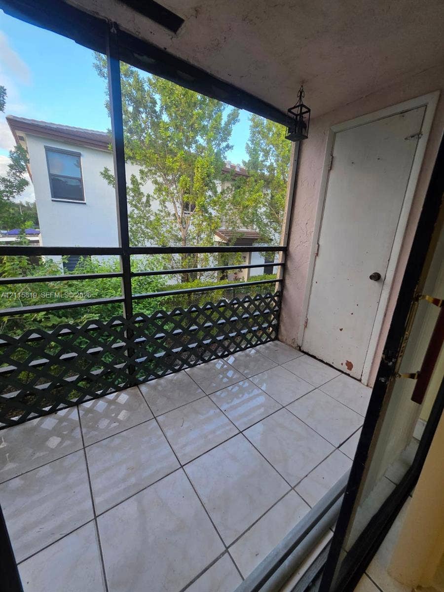831 NE 207th Lane, #2-203, Miami, Miami, FL 33179 Screened balcony featuring ceramic tile flooring, a black metal lattice railing, and a private storage closet