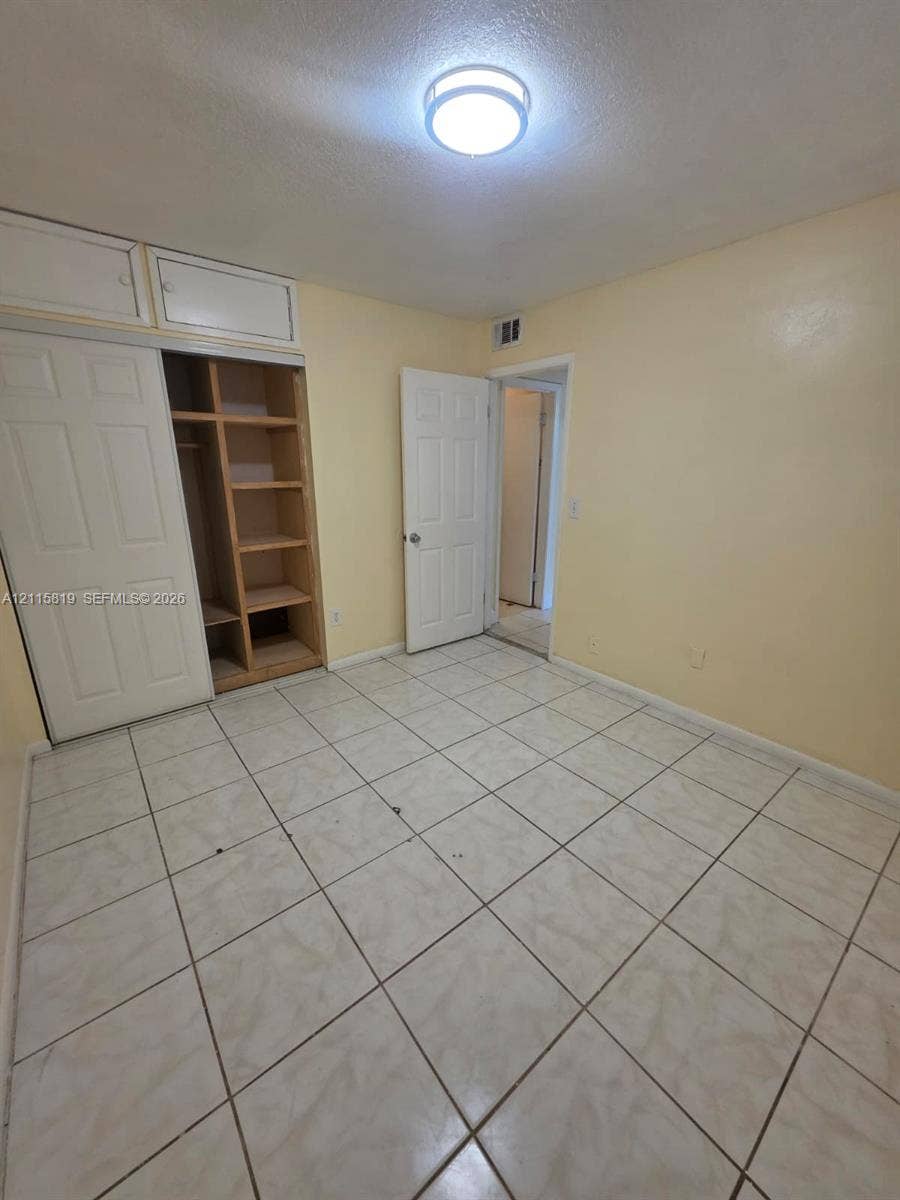 831 NE 207th Lane, #2-203, Miami, Miami, FL 33179 Room featuring neutral tile flooring, built-in shelving with overhead storage cabinets, and a flush-mount ceiling light fixture