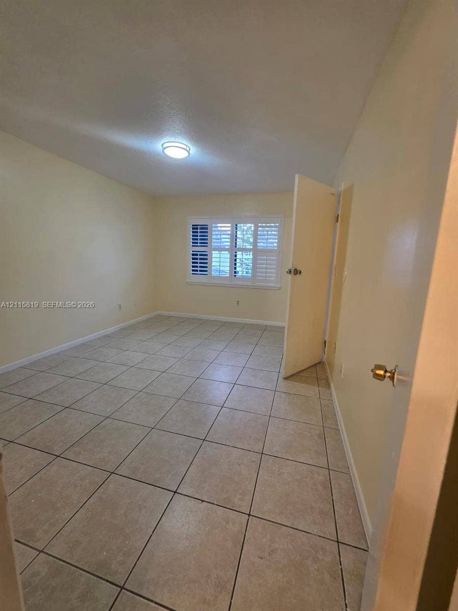 831 NE 207th Lane, #2-203, Miami, Miami, FL 33179 Room featuring neutral tile flooring, window with interior shutters, and ceiling-mounted lighting