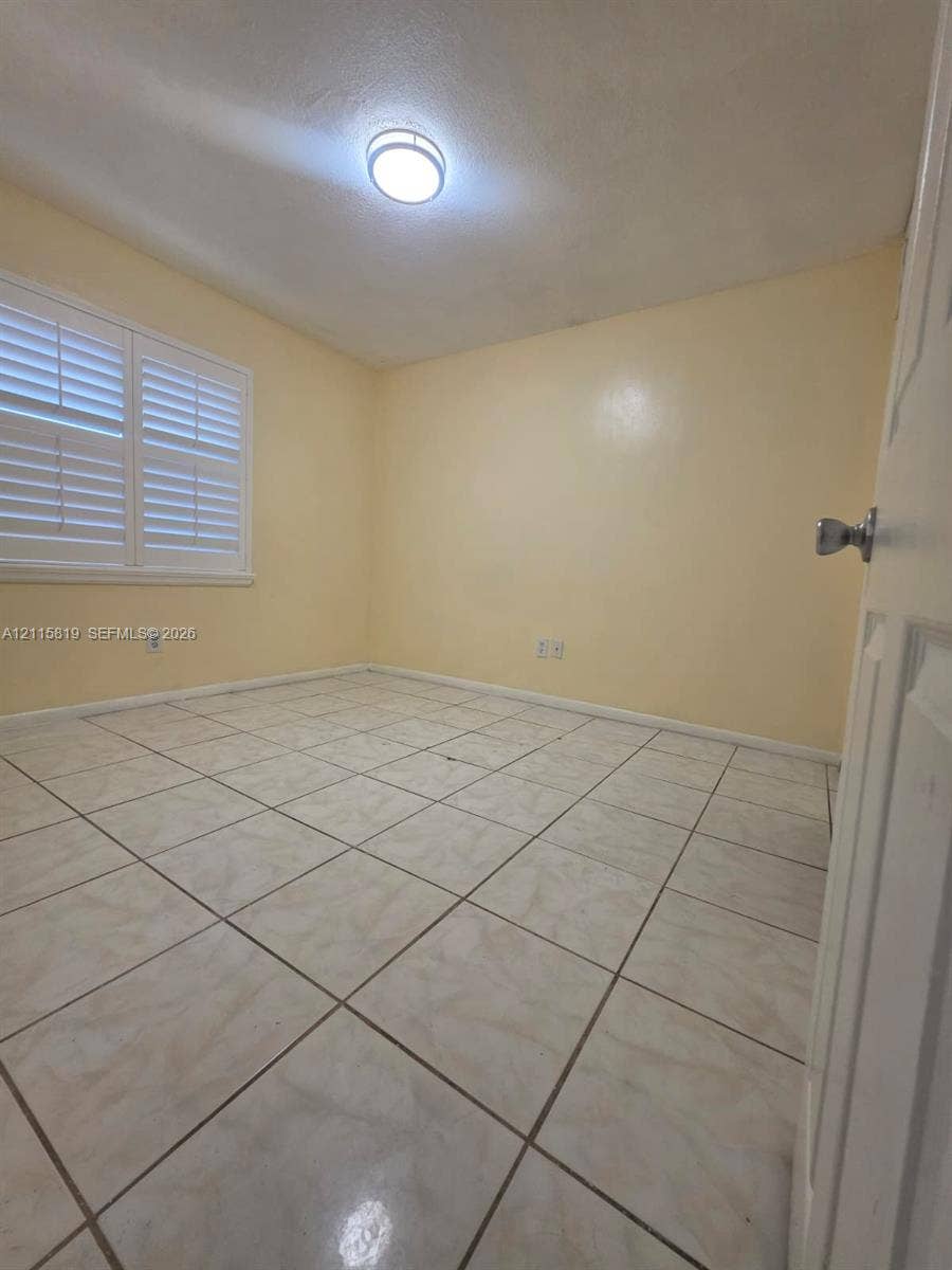 831 NE 207th Lane, #2-203, Miami, Miami, FL 33179 Room featuring tile flooring, plantation shutters, and a ceiling-mounted light fixture