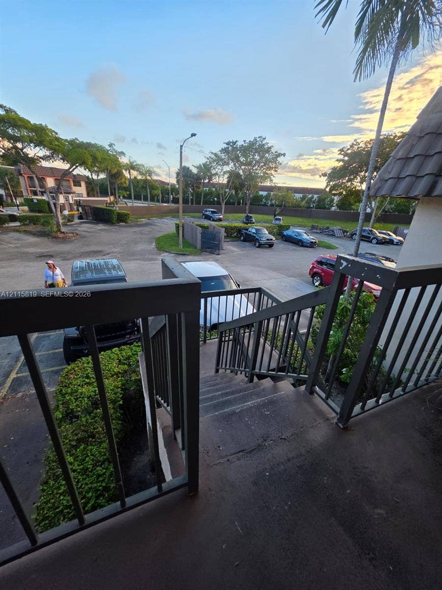 831 NE 207th Lane, #2-203, Miami, Miami, FL 33179 Exterior staircase with dark-toned metal railings overlooking a paved parking area