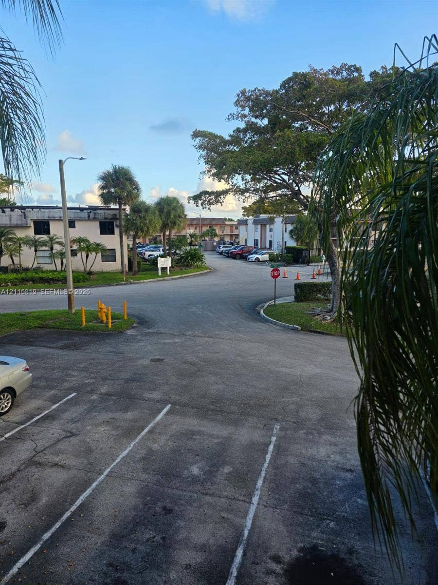 831 NE 207th Lane, #2-203, Miami, Miami, FL 33179 Asphalt parking area featuring painted stalls, mature palm trees, and manicured landscaping