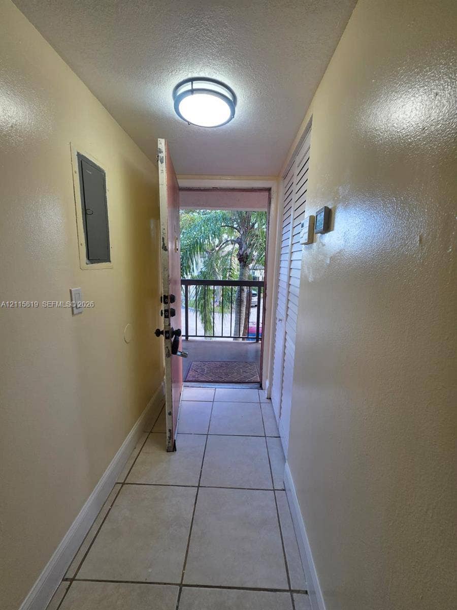 831 NE 207th Lane, #2-203, Miami, Miami, FL 33179 Entryway featuring large-format tile flooring, a flush-mount circular ceiling light fixture, and floor-to-ceiling louvered closet doors
