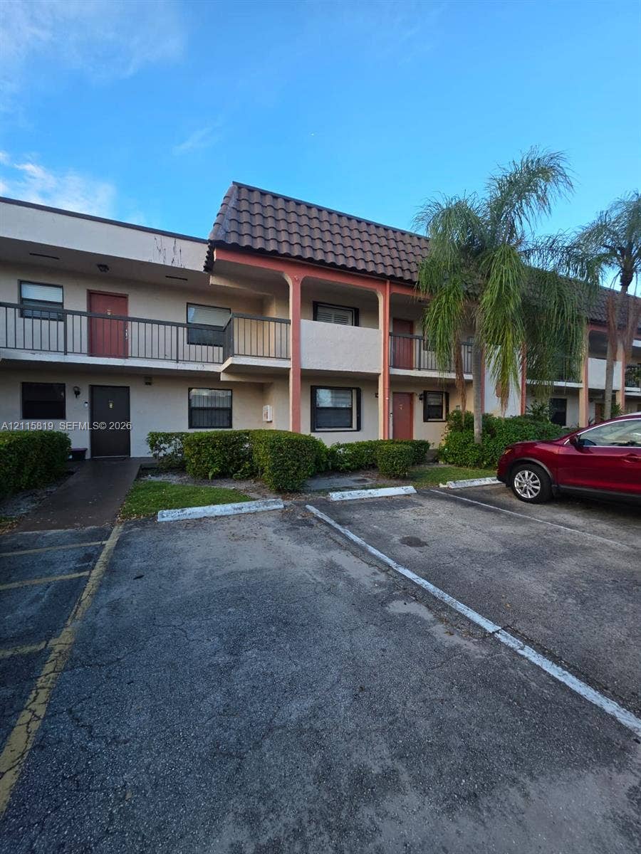 831 NE 207th Lane, #2-203, Miami, Miami, FL 33179 Two-story exterior featuring a mansard roofline, metal balcony railings, and paved surface parking