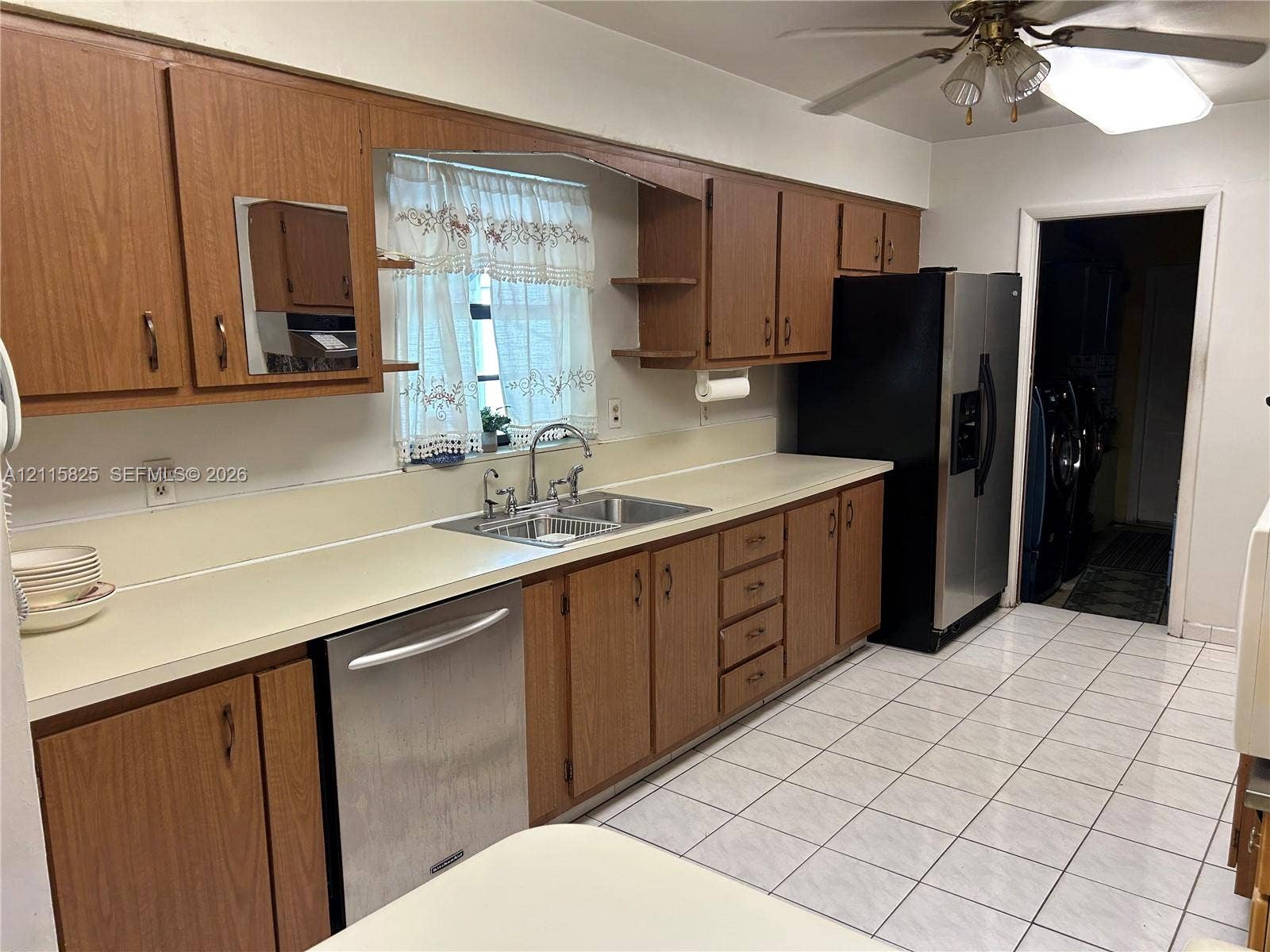 7130 W 12th Court, Hialeah, FL 33014 Kitchen featuring wood cabinetry, stainless steel dishwasher, double-basin sink with arched faucet, ceramic tile flooring, and integrated ceiling fan