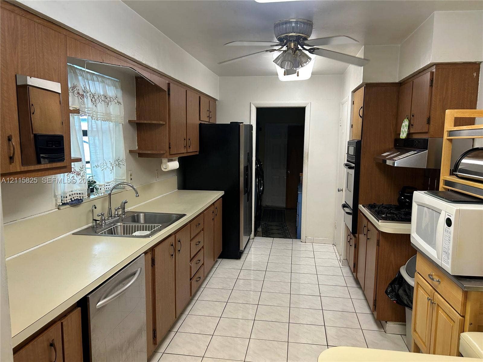 7130 W 12th Court, Hialeah, FL 33014 Kitchen featuring wood cabinetry, solid-surface countertops, stainless steel sink with gooseneck faucet, tile flooring, and integrated wall oven