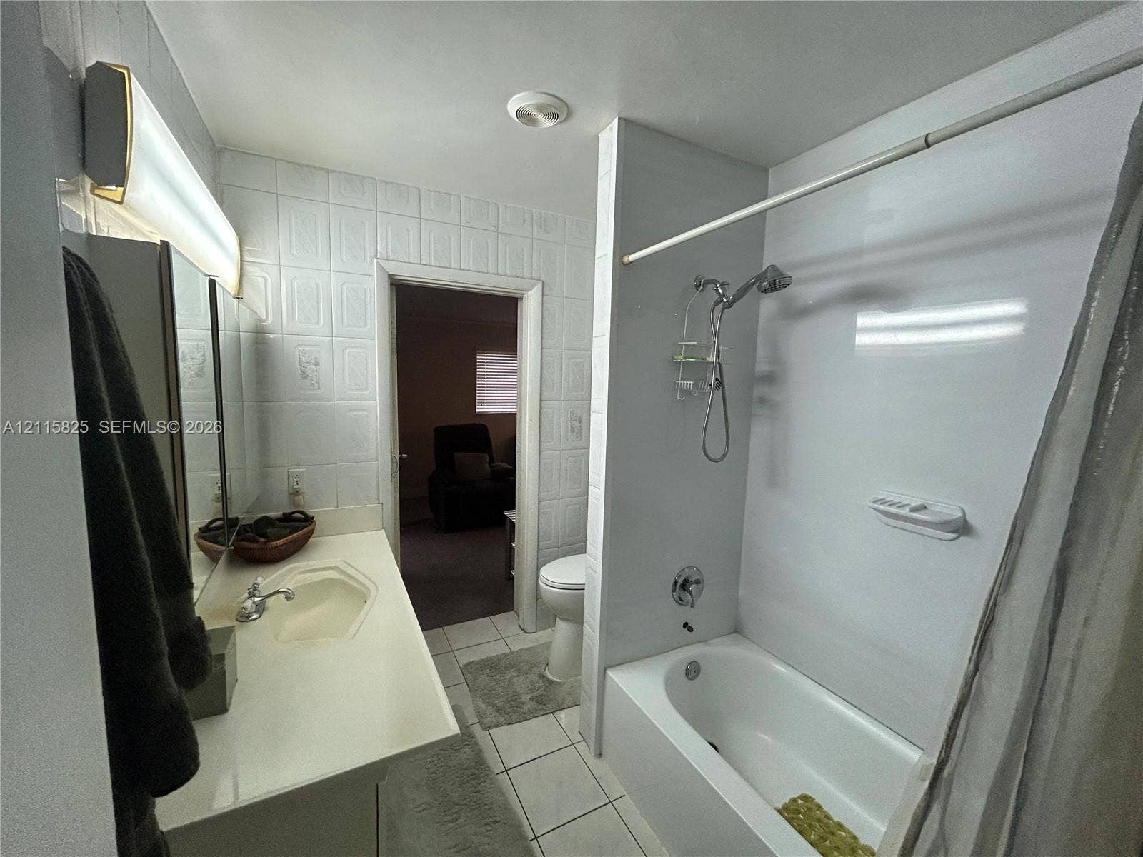 7130 W 12th Court, Hialeah, FL 33014 Bathroom featuring a white vanity with an integrated sink, polished chrome faucet, tiled wall surround, and a tub-shower combination with a wall-mounted shower head