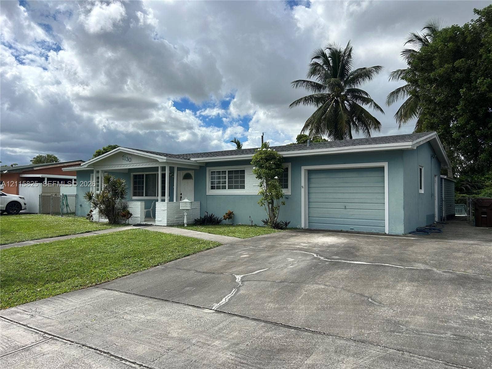7130 W 12th Court, Hialeah, FL 33014 Single-story exterior featuring a covered front porch, attached garage, concrete driveway, and front lawn