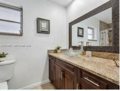 411 Wilma Circle, #0, Riviera Beach, Riviera Beach, FL 33404 Bathroom vanity featuring a stone-finish countertop, glass vessel sink, polished chrome faucet, dark wood-finish cabinetry, and a framed mirror