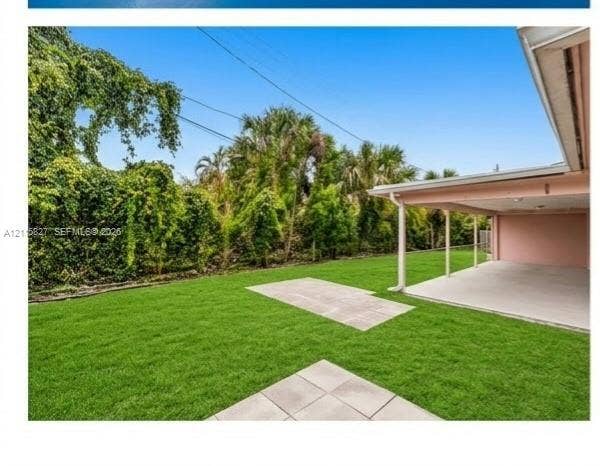 411 Wilma Circle, #0, Riviera Beach, Riviera Beach, FL 33404 Backyard featuring a concrete patio, covered porch area, manicured lawn, and dense mature perimeter landscaping