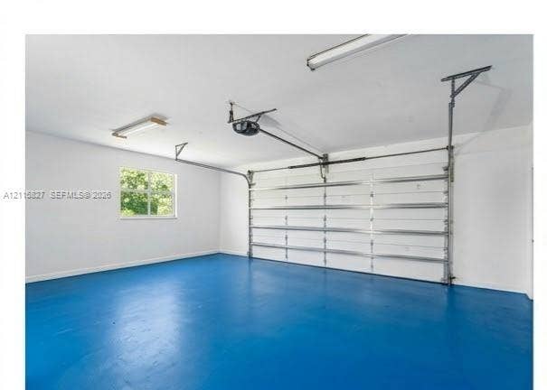 411 Wilma Circle, #0, Riviera Beach, Riviera Beach, FL 33404 Garage interior featuring a painted concrete floor, white-finished walls, an automated sectional door, and overhead lighting
