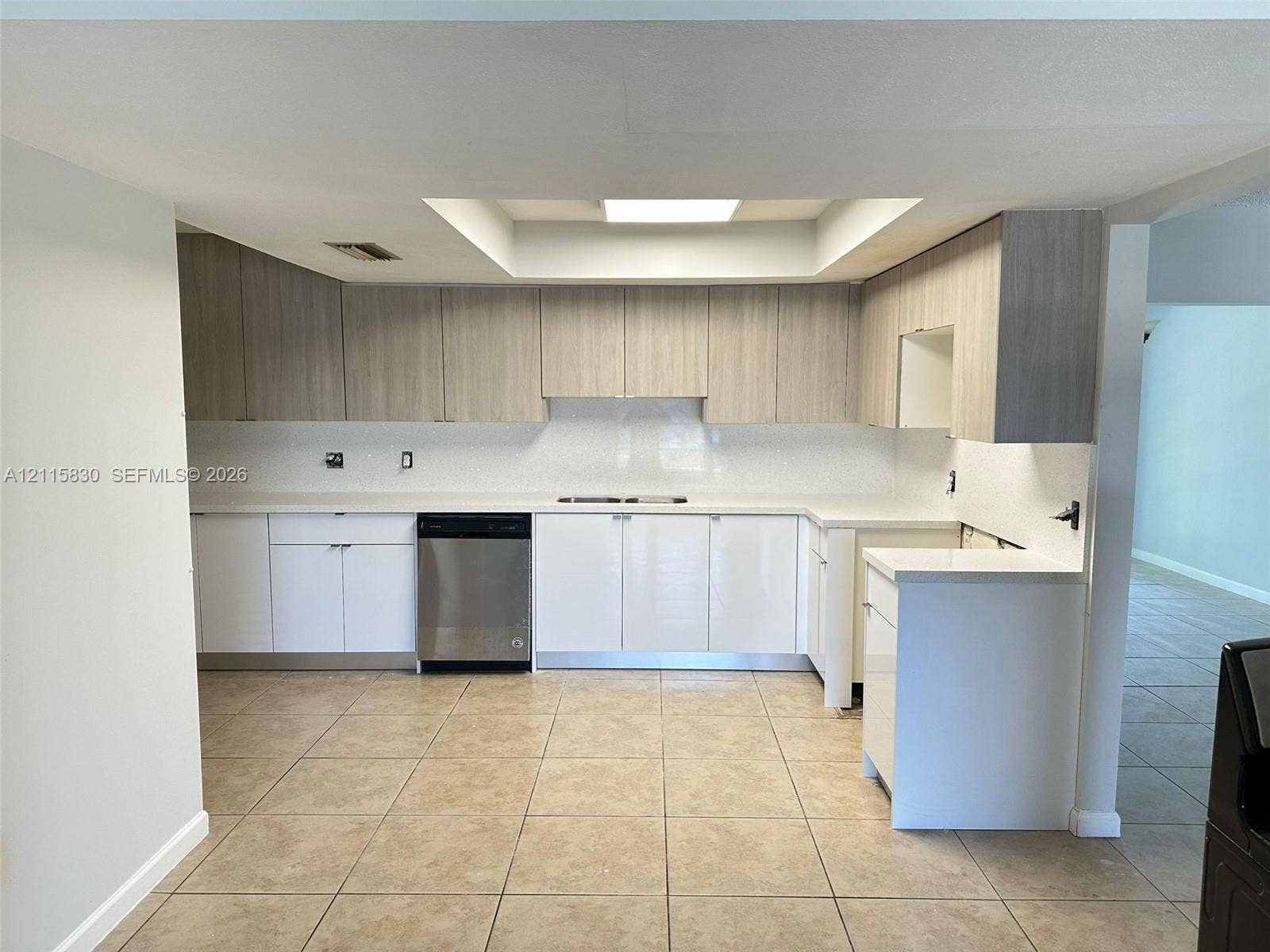 9061 NW 25th Court, #0, Sunrise, Sunrise, FL 33322 Kitchen featuring two-tone cabinetry with wood-finish uppers and white lower cabinets, solid-surface countertops, tile flooring, and built-in dishwasher