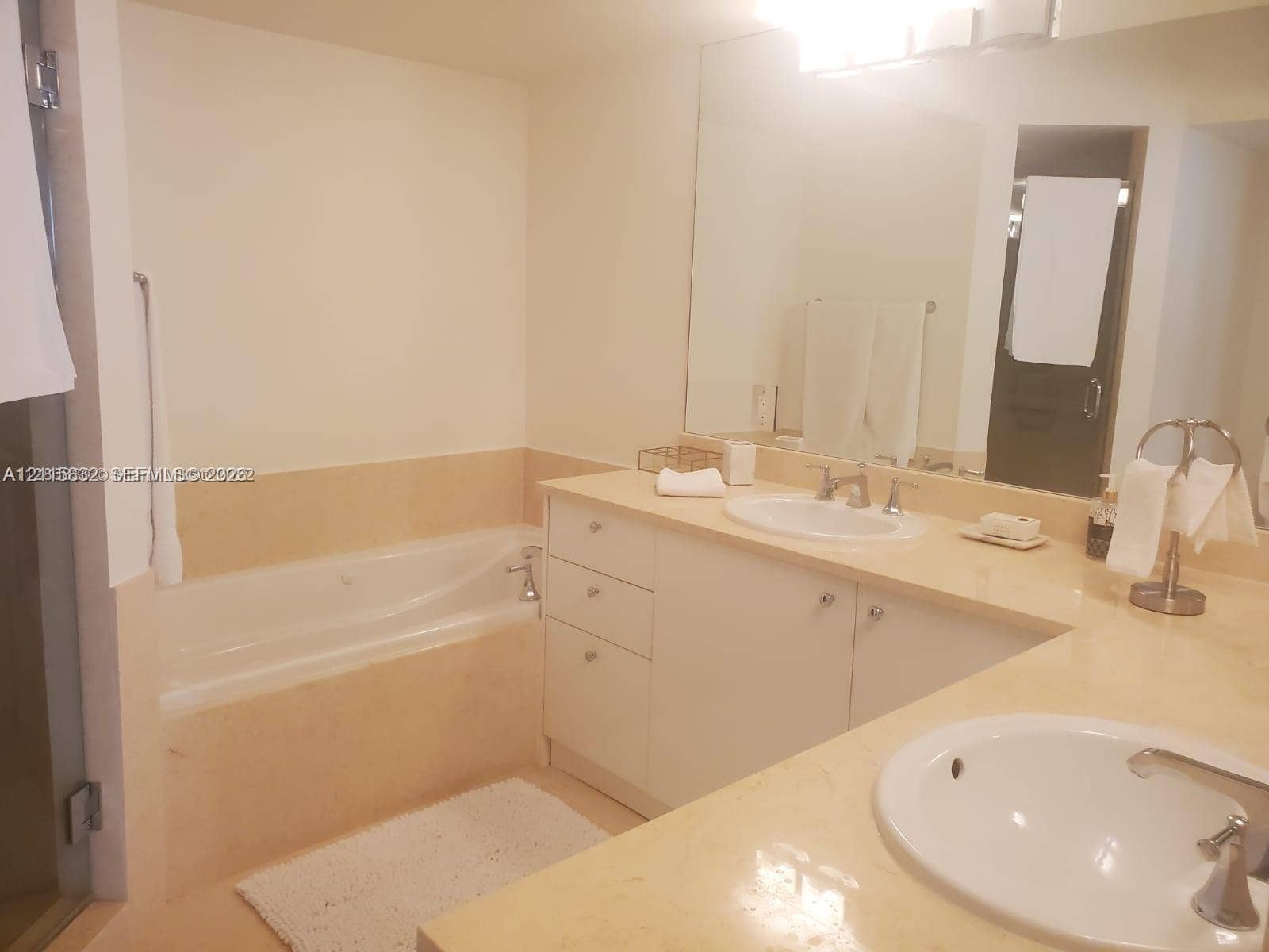19900 E Country Club Drive, #607, Aventura, Aventura, FL 33180 Bathroom featuring dual drop-in sinks, stone-finish countertops, built-in cabinetry, and a jetted soaking tub