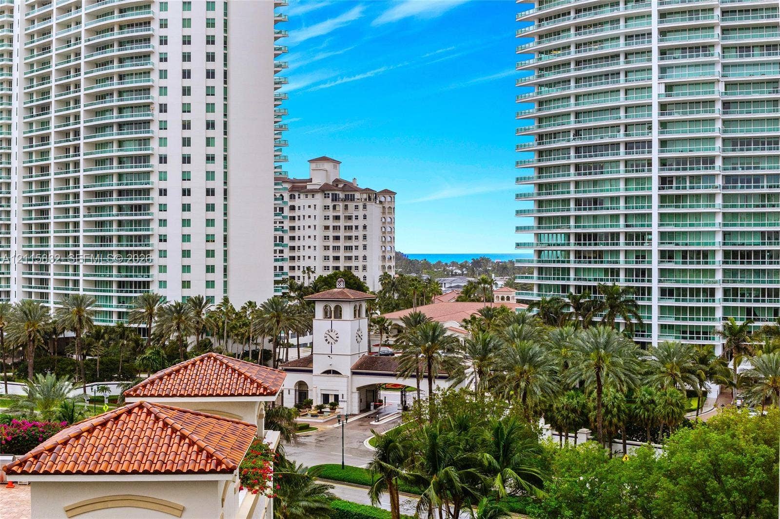 19900 E Country Club Drive, #607, Aventura, Aventura, FL 33180 High-rise towers featuring glass-paneled balconies, terracotta-tiled roof accents, clock tower architectural detail, and mature palm landscaping