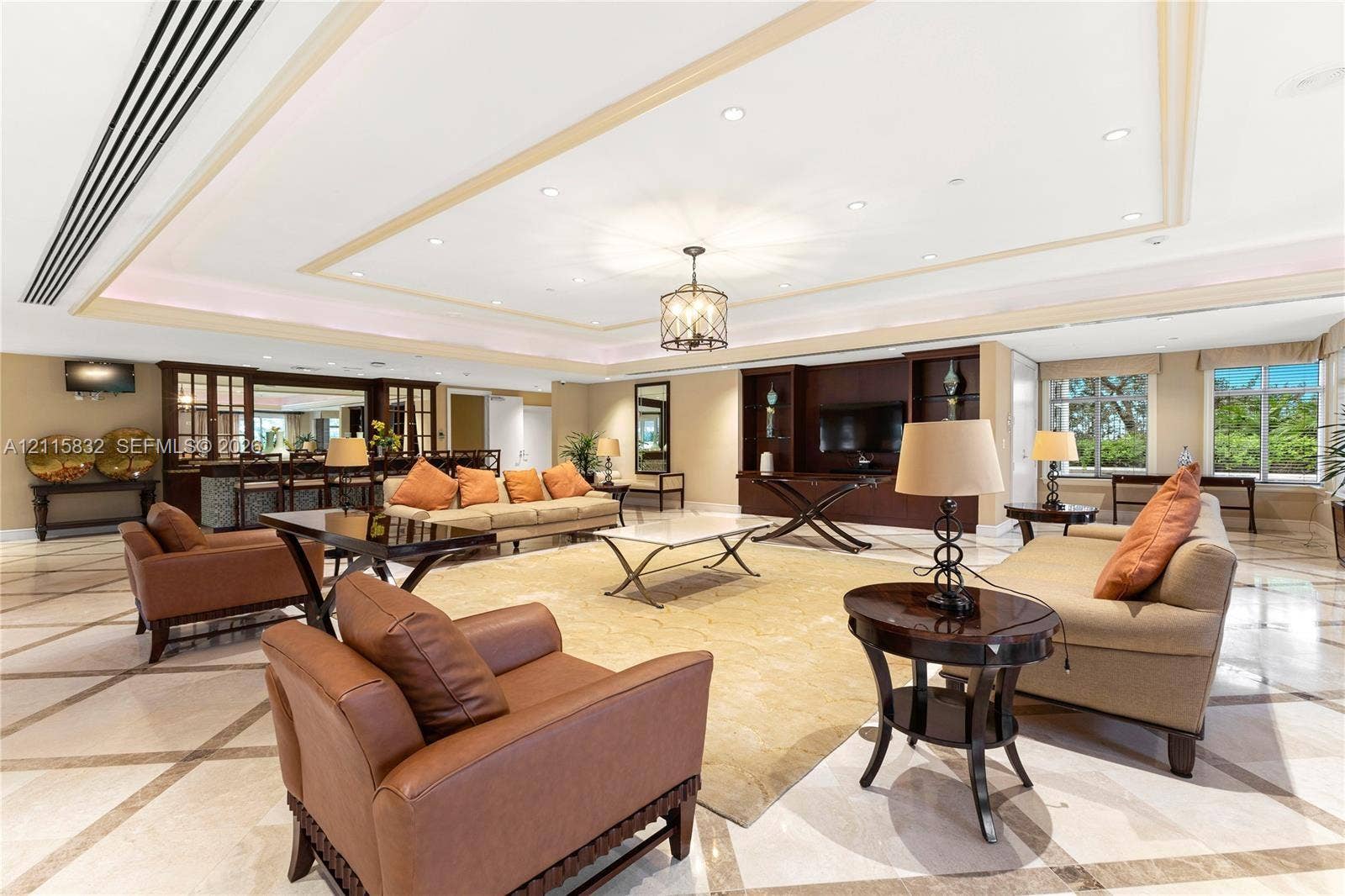 19900 E Country Club Drive, #607, Aventura, Aventura, FL 33180 Spacious living area featuring stone tile flooring with a geometric inlay pattern, a tray ceiling with recessed lighting, an integrated wet bar with glass-front cabinetry, and custom built-in shelving