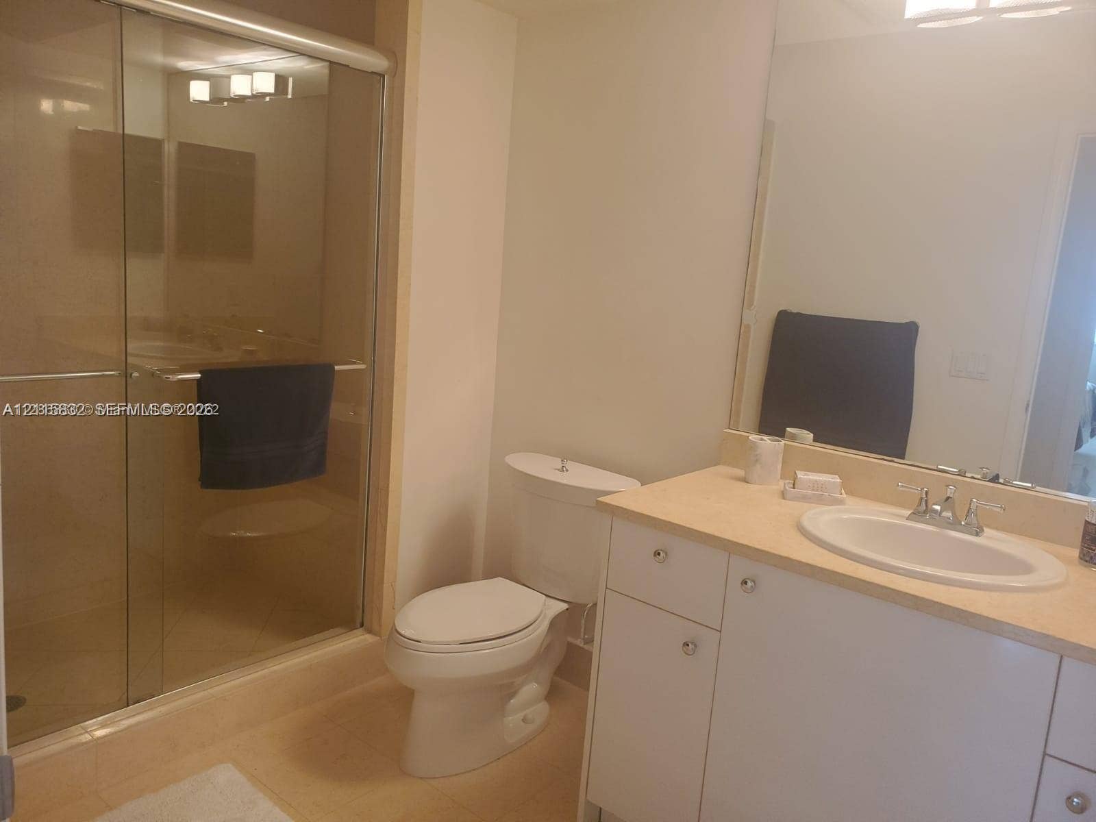 19900 E Country Club Drive, #607, Aventura, Aventura, FL 33180 Bathroom featuring a vanity with an integrated oval sink, a large wall-mounted mirror, a two-piece commode, and a shower enclosed by sliding glass doors