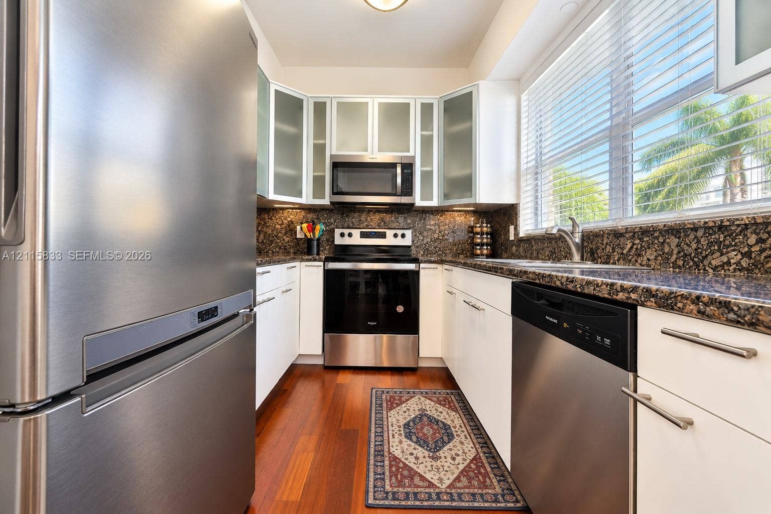 929 Meridian Avenue, #5, Miami Beach, FL 33139 Kitchen featuring stainless steel appliances, dark stone countertops, white cabinetry with frosted glass inserts, and wood-finish flooring