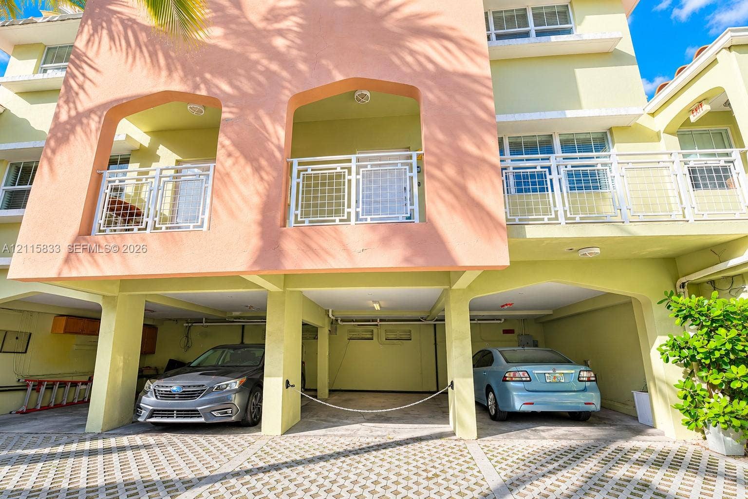 929 Meridian Avenue, #5, Miami Beach, FL 33139 Multi-level exterior featuring stucco facade, recessed private balconies with metal railings, and covered ground-level parking with permeable paver surface