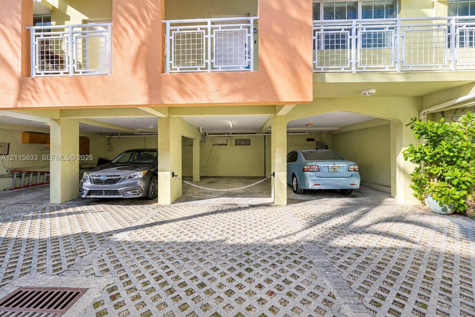 929 Meridian Avenue, #5, Miami Beach, FL 33139 Covered parking area featuring concrete lattice pavers, structural support pillars, and upper-level balconies with white railings