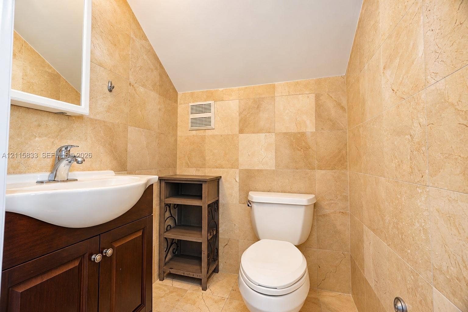 929 Meridian Avenue, #5, Miami Beach, FL 33139 Bathroom featuring full-height stone wall tiling, wood-finish cabinetry, wall-mounted mirror, and a ceramic pedestal sink