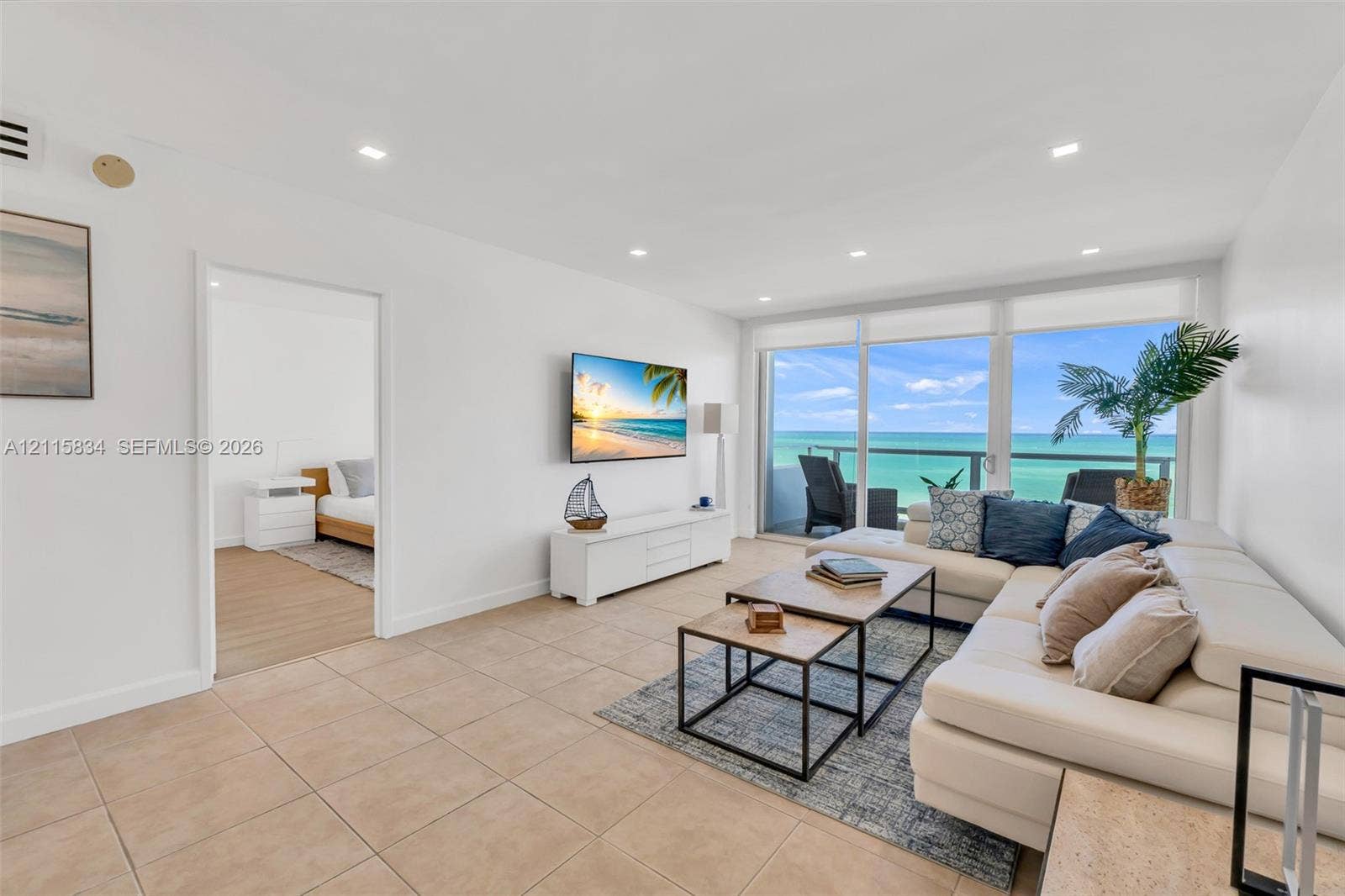 5161 Collins Avenue, #1717, Miami Beach, Miami Beach, FL 33140 Living area featuring large-format neutral floor tiling, recessed lighting, and floor-to-ceiling glass doors opening to a balcony with an ocean backdrop