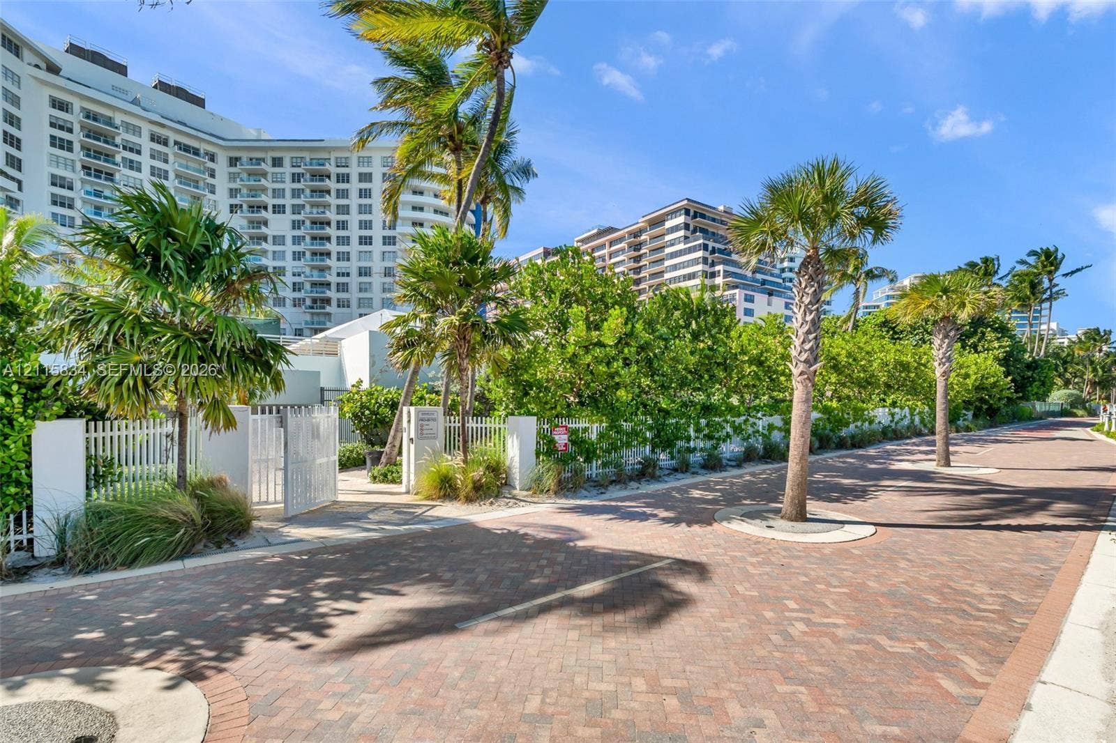 5161 Collins Avenue, #1717, Miami Beach, Miami Beach, FL 33140 Brick-paved thoroughfare featuring mature palm trees, white metal fencing, and stone perimeter pillars