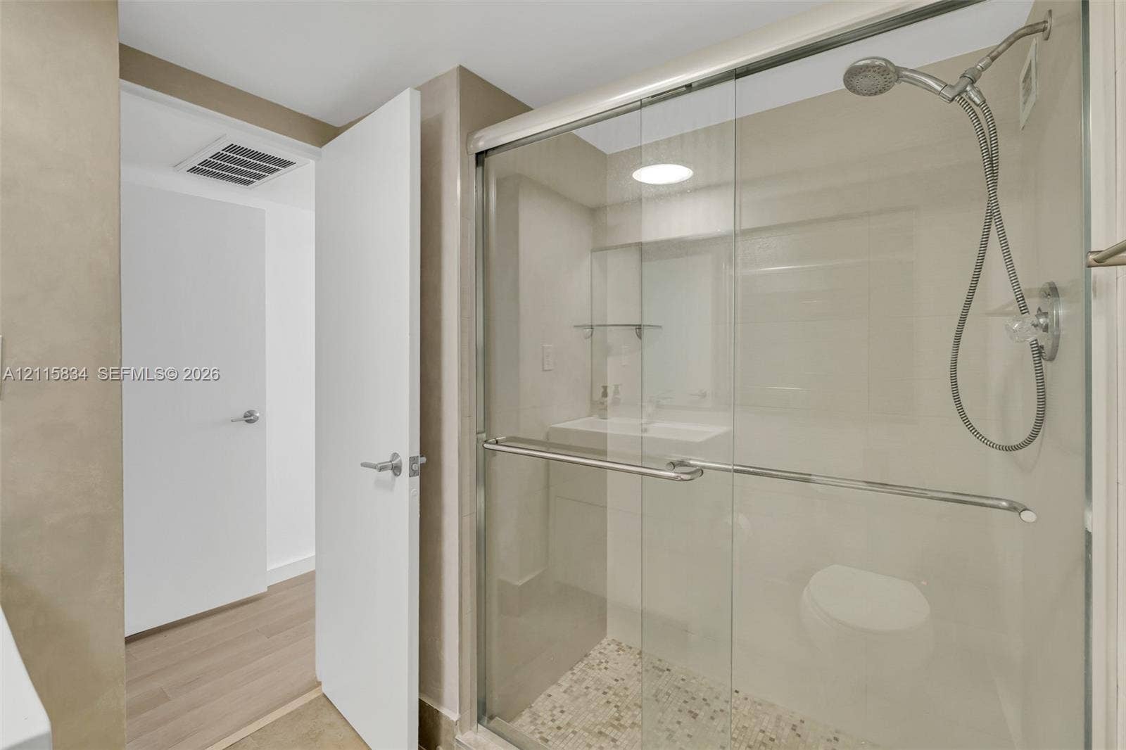 5161 Collins Avenue, #1717, Miami Beach, Miami Beach, FL 33140 Walk-in shower with a glass enclosure, polished metal hardware, handheld showerhead, and pebble-style floor tiling