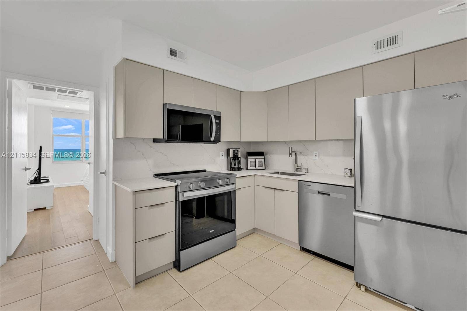 5161 Collins Avenue, #1717, Miami Beach, Miami Beach, FL 33140 Kitchen featuring flat-panel cabinetry, quartz countertops, veined stone-style backsplash, and stainless steel appliances