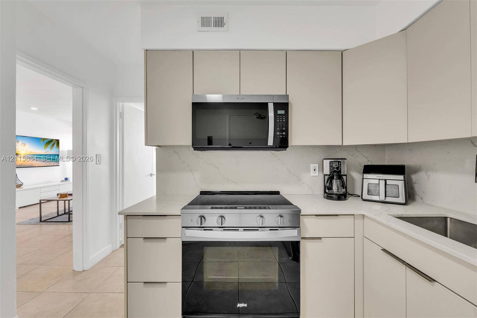 5161 Collins Avenue, #1717, Miami Beach, Miami Beach, FL 33140 Kitchen featuring flat-panel cabinetry, light-toned stone-finish countertops, full-height stone-finish backsplash, and stainless steel appliances